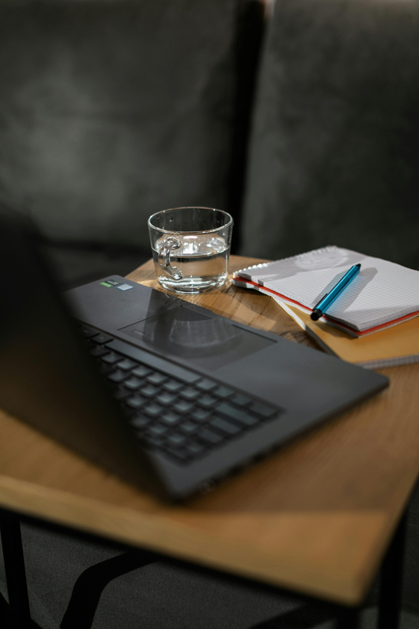 laptop with notepad and pen and glass of water